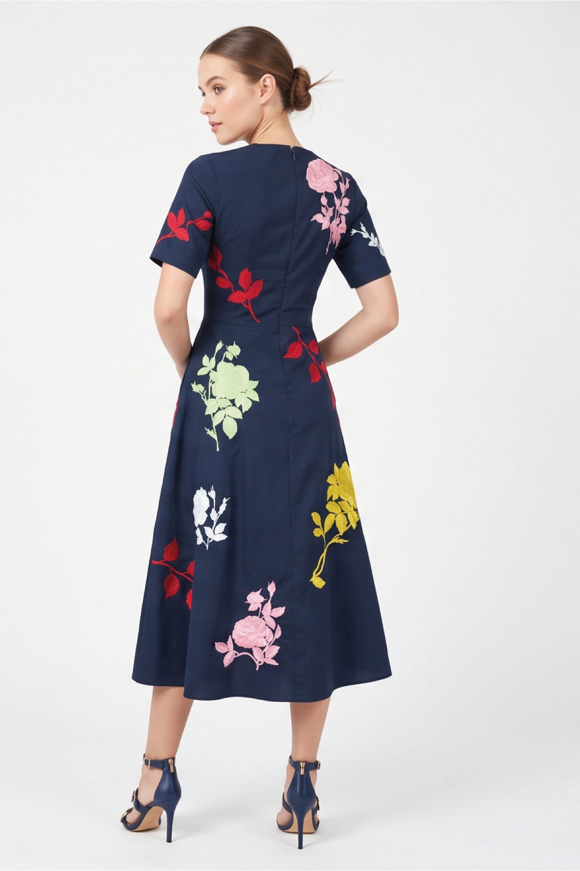 Back view of model wearing Fanm Mon Gandi Dress in navy with a concealed center-back zipper and multicolored floral embroidery across the bodice and A-line skirt