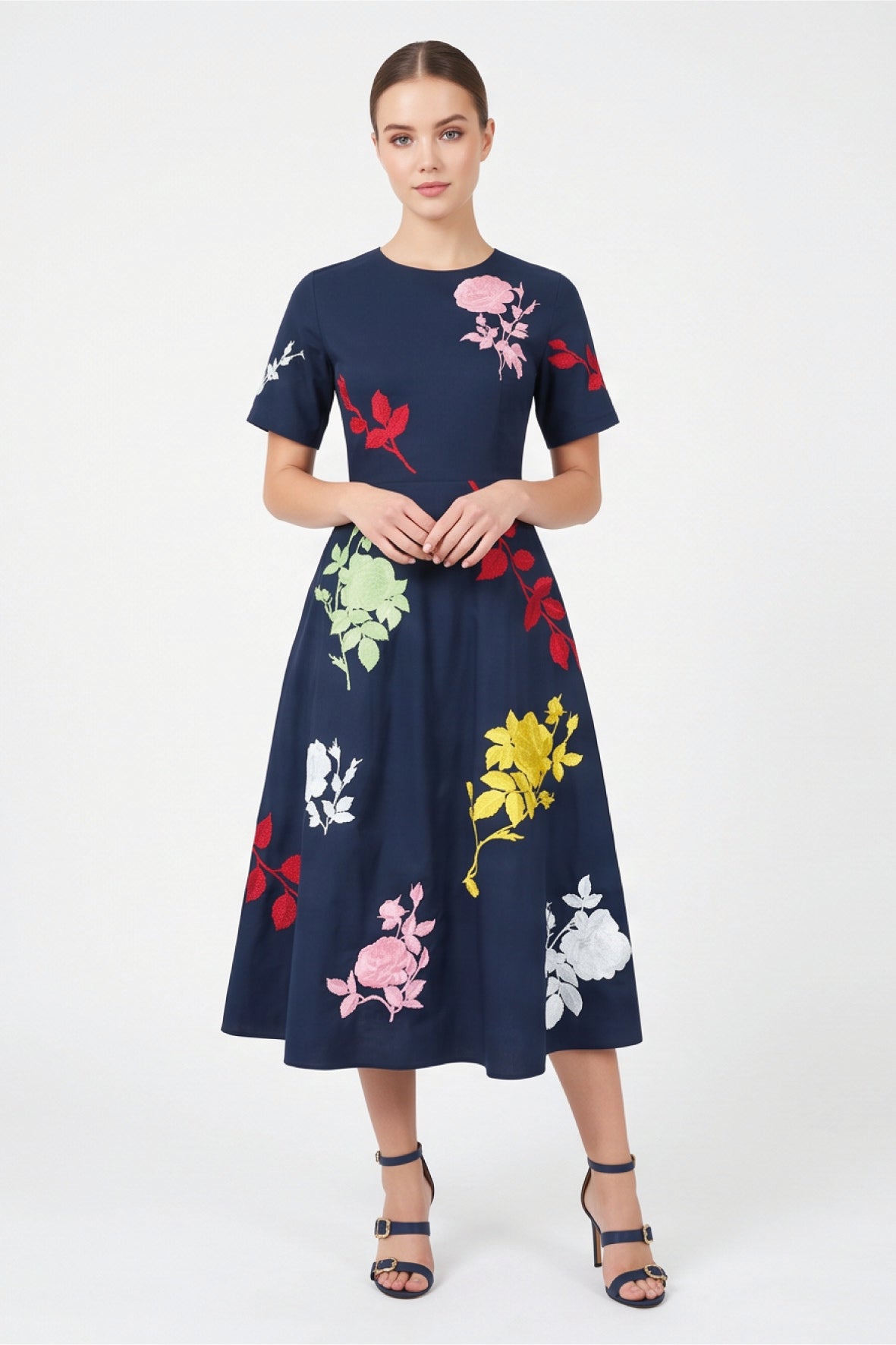 Model wearing Fanm Mon Gandi Dress in navy featuring a fitted waist, short sleeves, flowing A-line midi skirt, and pink, red, yellow, green, and white floral embroidery