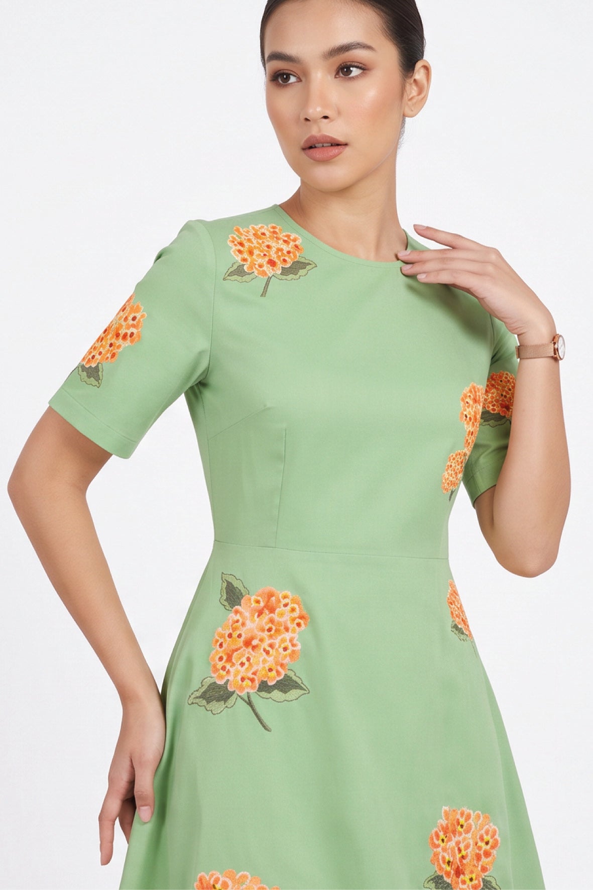 Detail of model wearing the Fanm Mon Gemlik Dress with intricate orange hydrangea embroidery across the bodice and sleeves.
