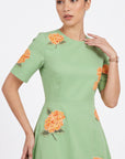 Detail of model wearing the Fanm Mon Gemlik Dress with intricate orange hydrangea embroidery across the bodice and sleeves.
