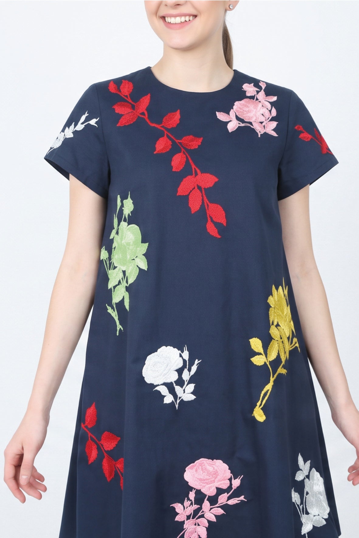 Close-up of the Fanm Mon Gence Dress in navy highlighting pink rose embroidery, red botanical stems, and colorful floral motifs across the bodice
