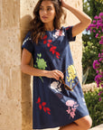 Model wearing the Fanm Mon Gence Dress in navy with colorful rose and botanical embroidery, short sleeves, and a relaxed A-line silhouette