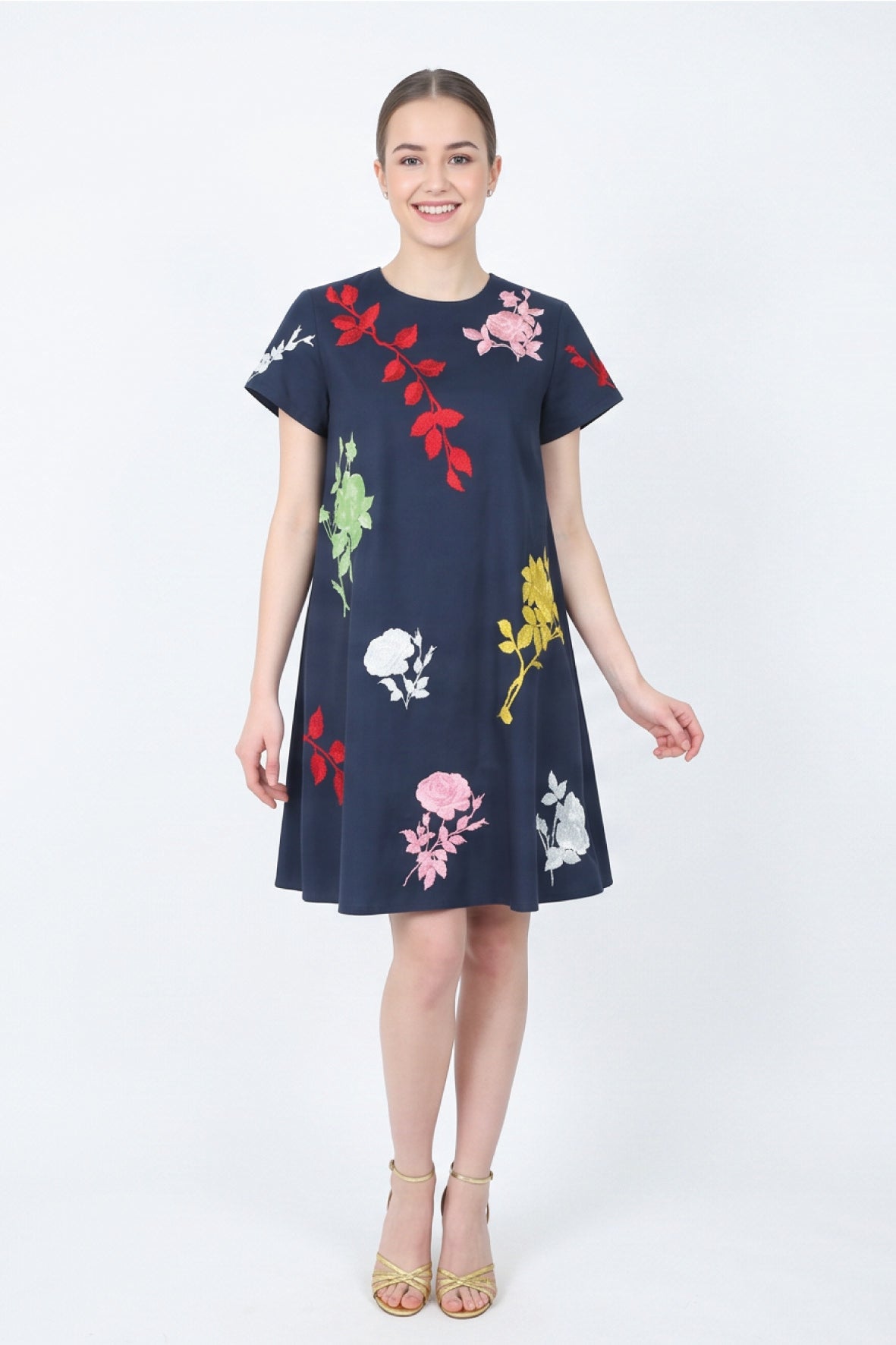 Model wearing the Fanm Mon Gence Dress in navy with a relaxed A-line silhouette and vibrant floral embroidery in pink, red, yellow, green, and white
