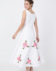 Back view of model wearing Fanm Mon Hazel Dress in white, showing the sleeveless bodice, concealed center-back zipper, defined waist, and pink rose embroidery across the full A-line midi skirt.