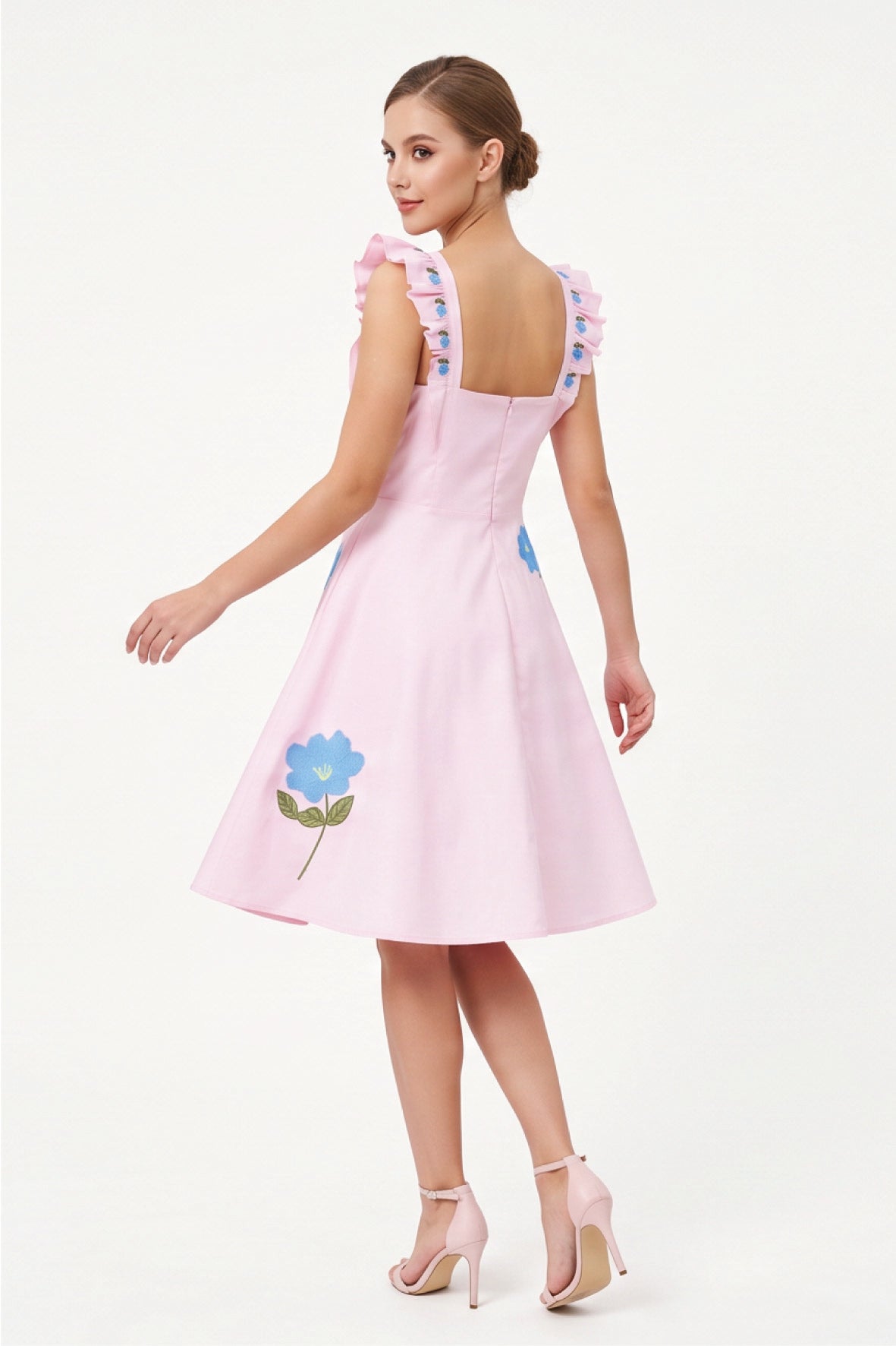 Back view of model wearing the Fanm Mon Hype Dress with embroidered ruffle straps and blue floral embroidery.
