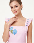 Detail of model wearing the Fanm Mon Hype Dress with blue floral embroidery and ruffled shoulder straps.