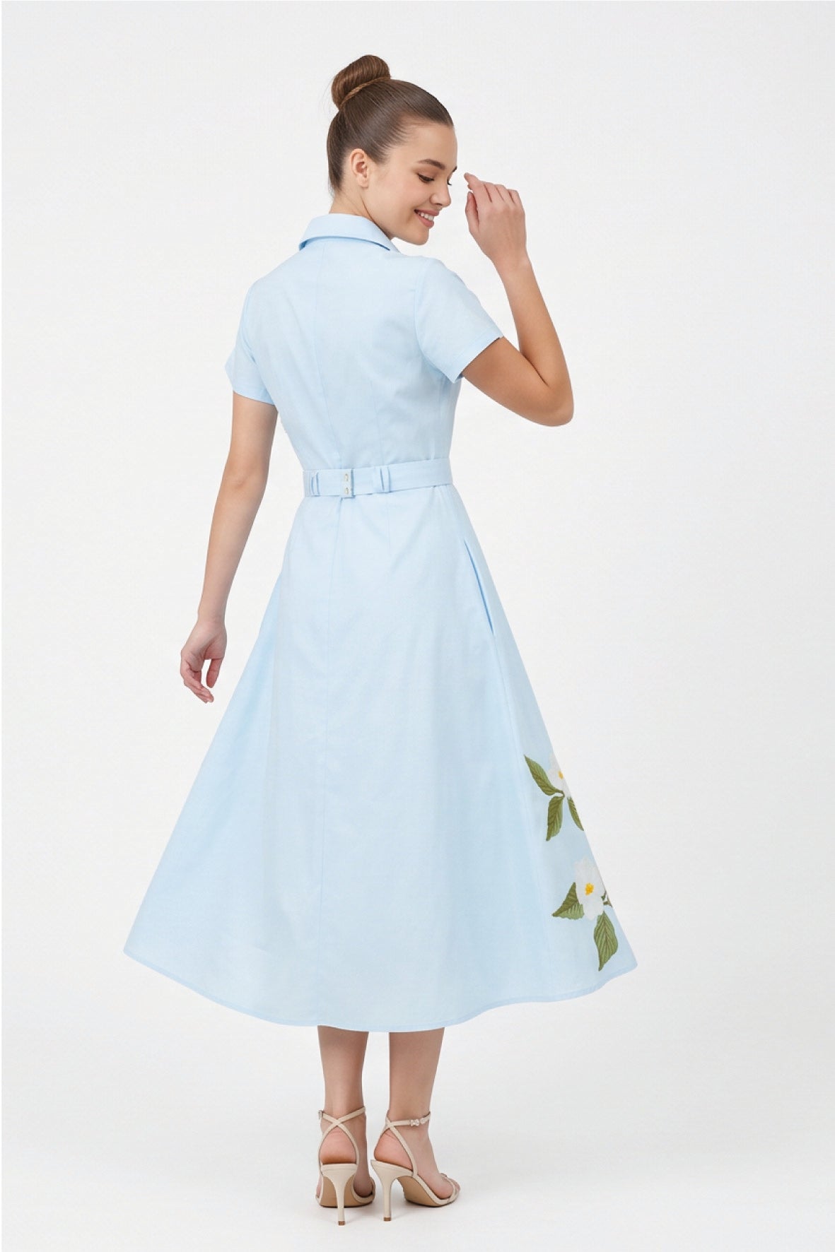 Back view of model wearing Fanm Mon Jahan Dress in light blue featuring an adjustable waist belt, tailored bodice, and flowing A-line midi skirt
