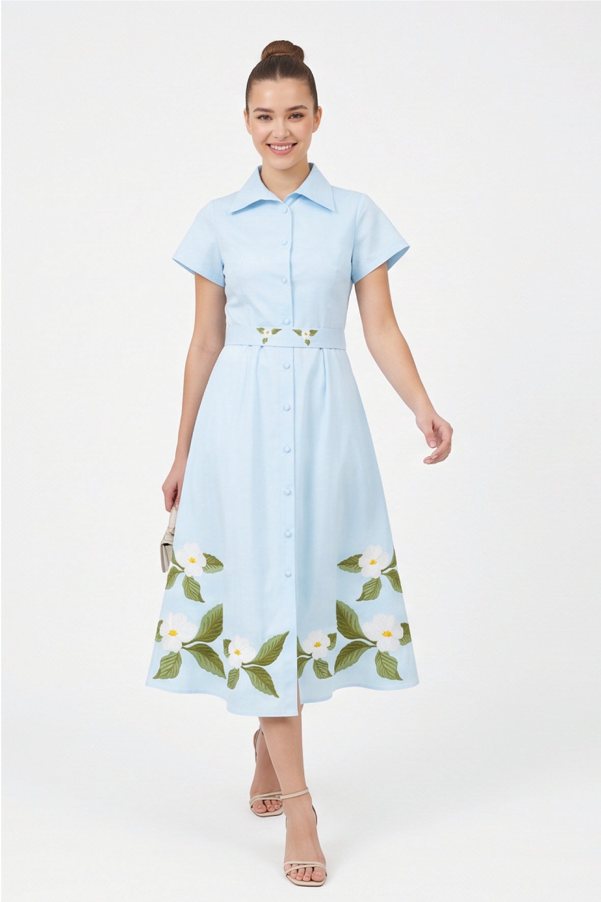 Model wearing Fanm Mon Jahan floral embroidered shirt dress in light blue with a button-front closure, defined waist, and white botanical embroidery along the hem