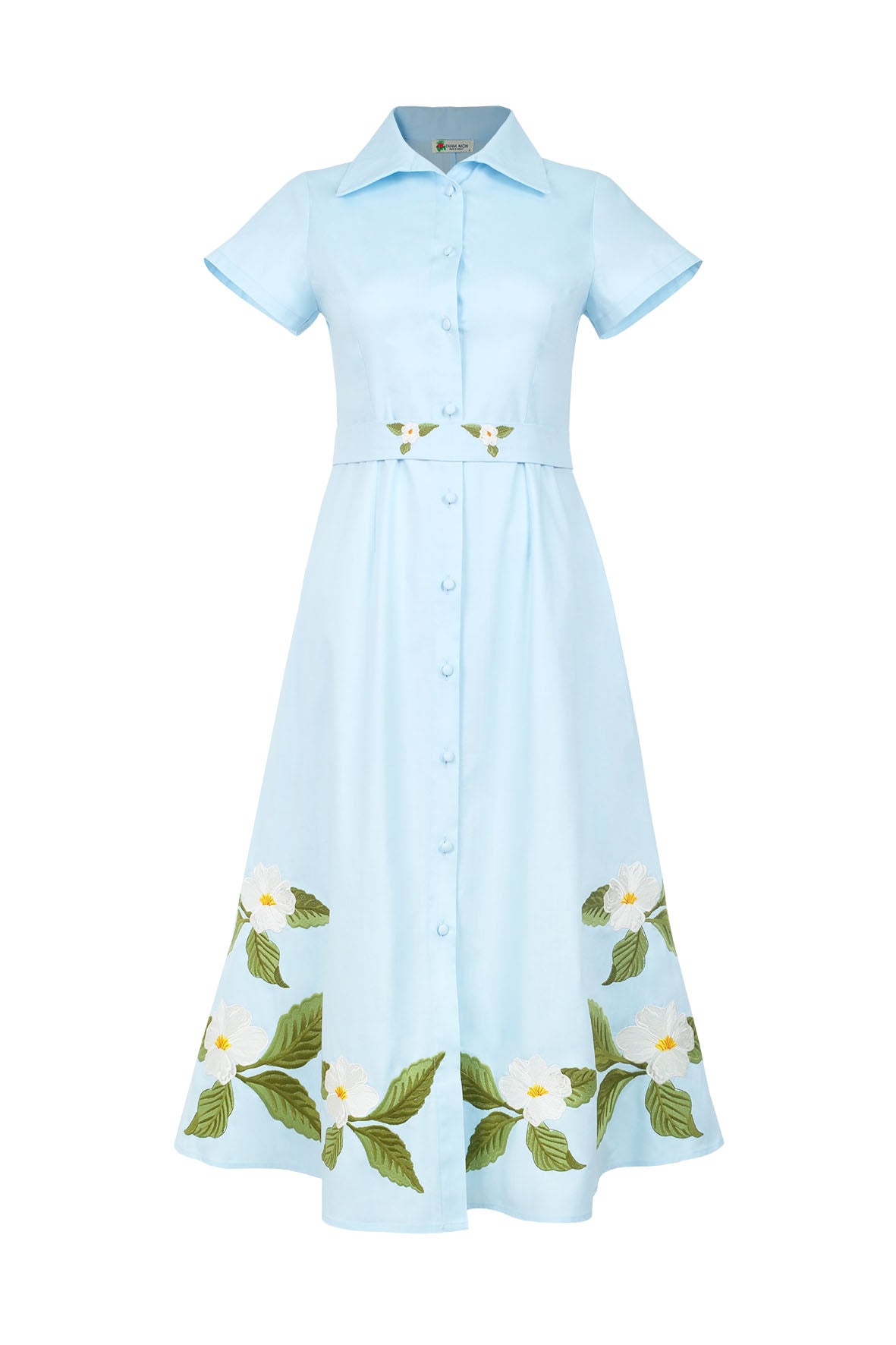 Fanm Mon Jahan Dress in light blue featuring a pointed collar, short sleeves, fabric-covered buttons, embroidered waist belt, and white floral embroidery along the midi skirt