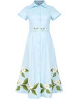 Fanm Mon Jahan Dress in light blue featuring a pointed collar, short sleeves, fabric-covered buttons, embroidered waist belt, and white floral embroidery along the midi skirt