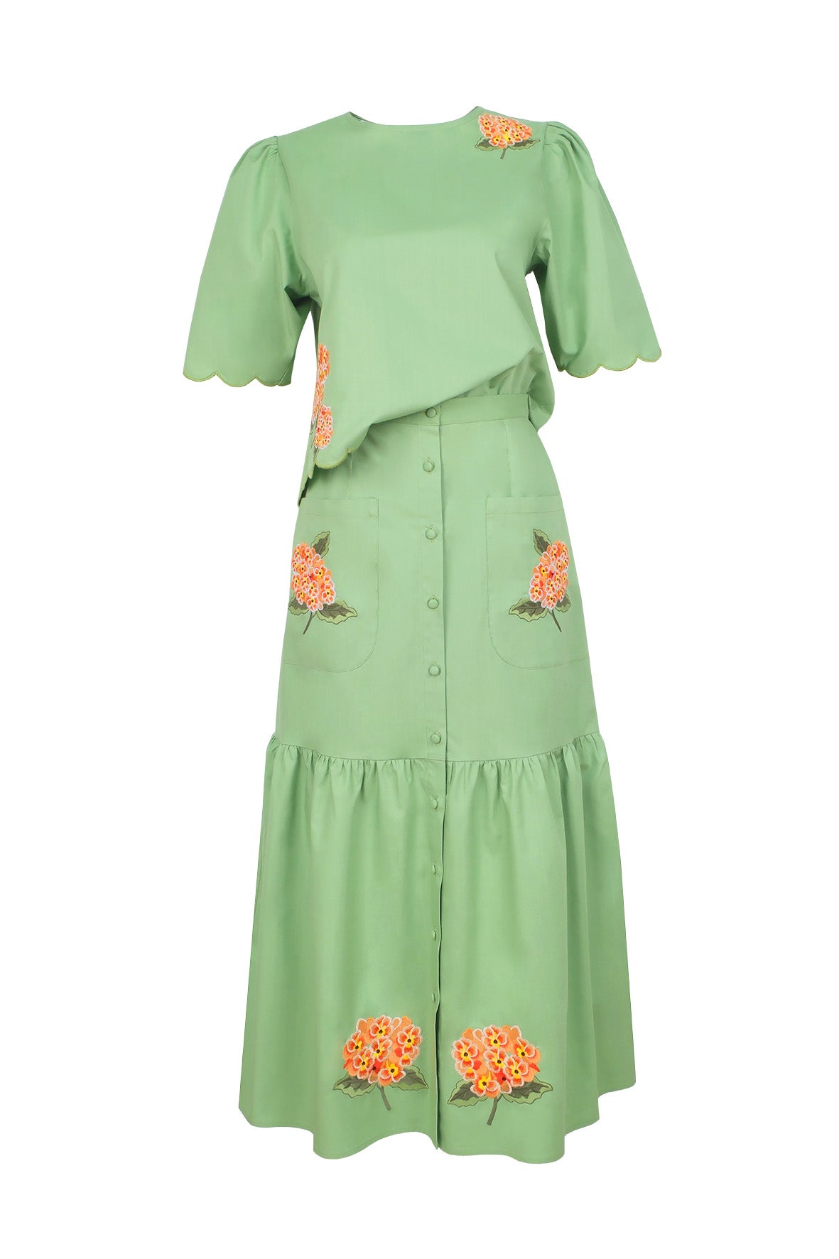 Fanm Mon Komarna Set in green featuring a short-sleeve scalloped top with botanical embroidery and a coordinating button-front midi skirt with embroidered patch pockets and a gathered hem