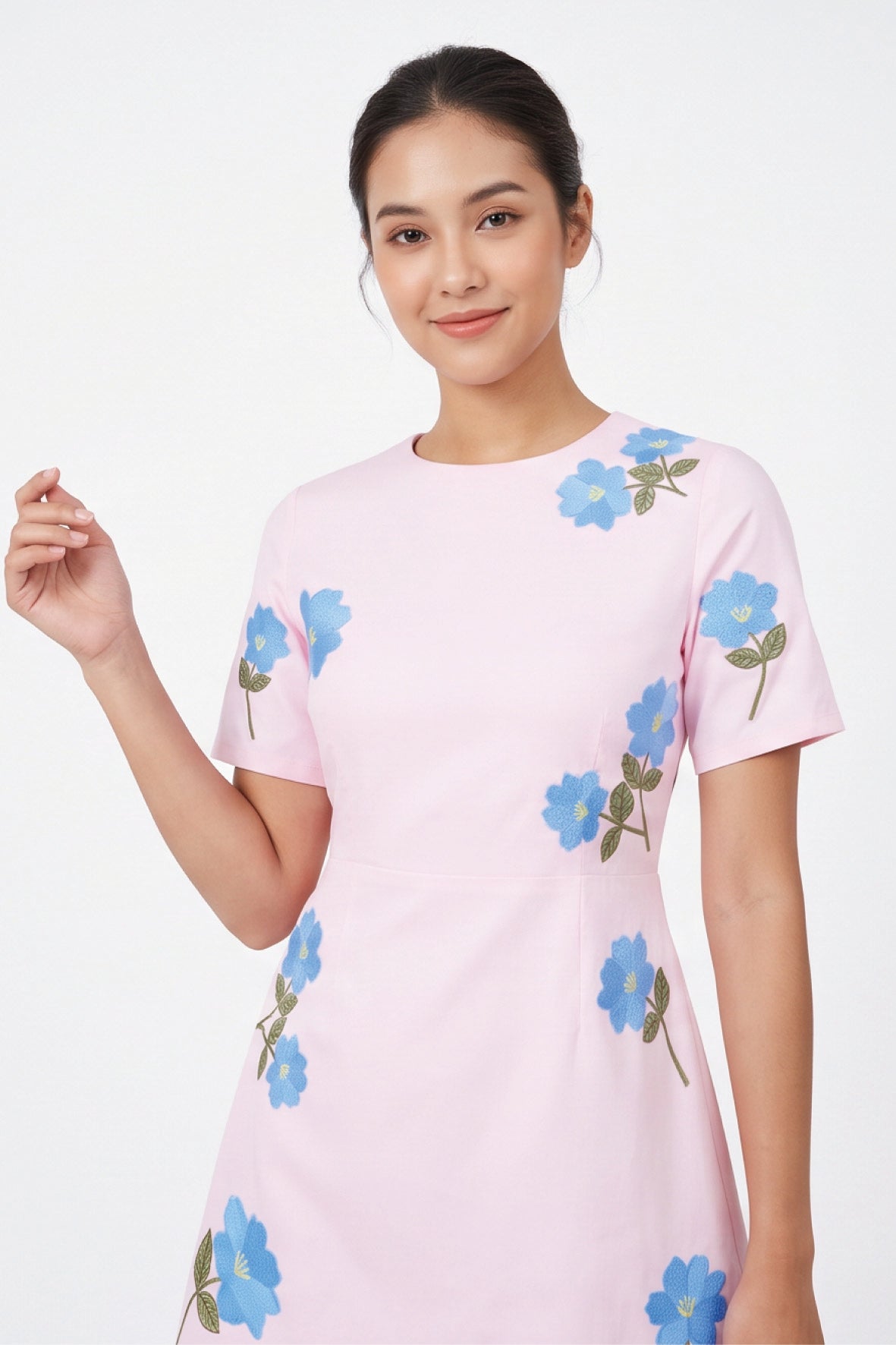 Detail of model wearing the Fanm Mon Kore Dress with blue floral embroidery accented by green leaves and yellow centers.