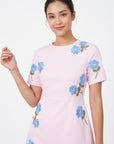 Detail of model wearing the Fanm Mon Kore Dress with blue floral embroidery accented by green leaves and yellow centers.
