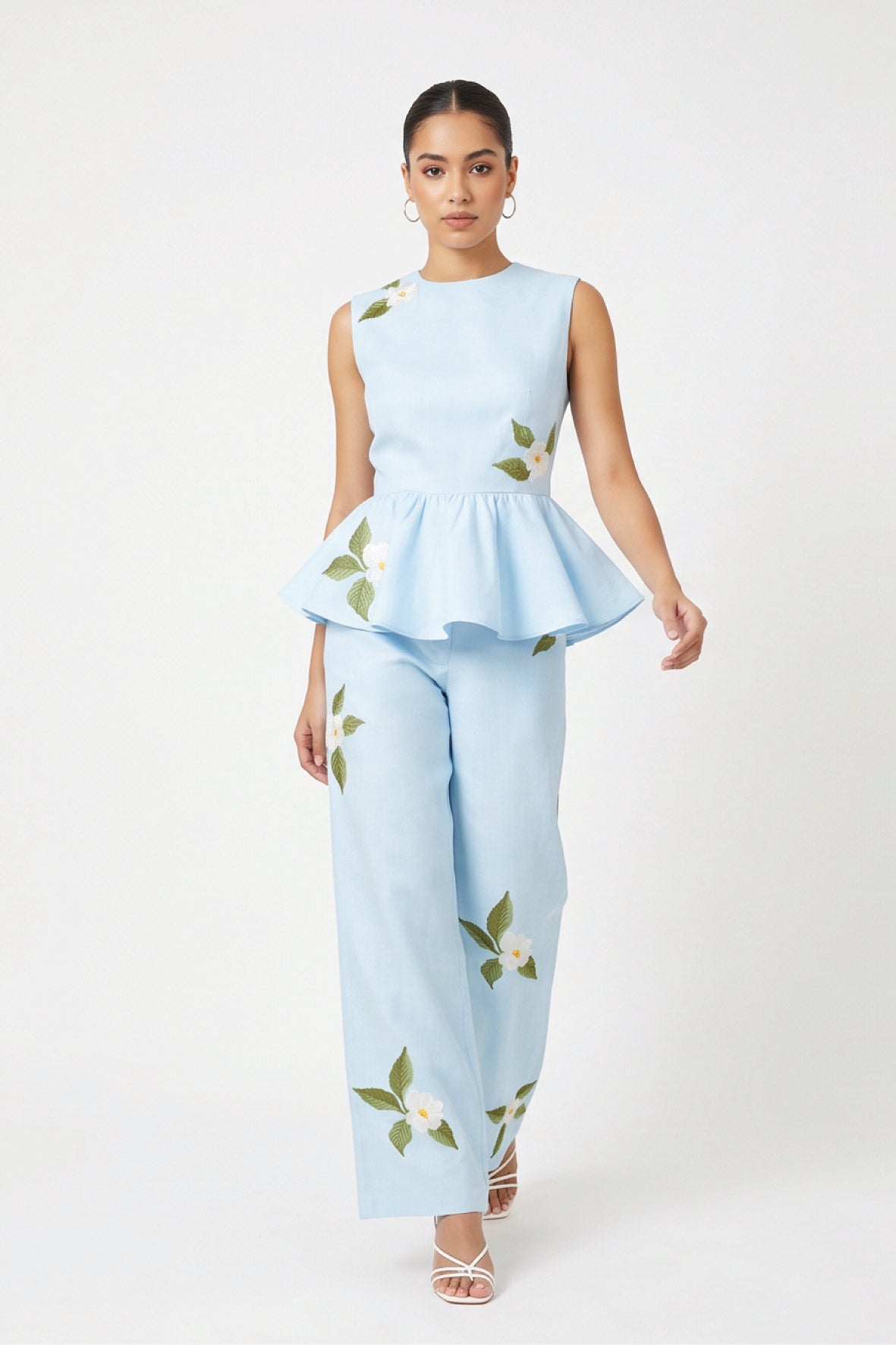 Model wearing Fanm Mon Malez Set in Light Lagoon featuring a sleeveless peplum top and wide-leg trousers with delicate white floral embroidery and green foliage