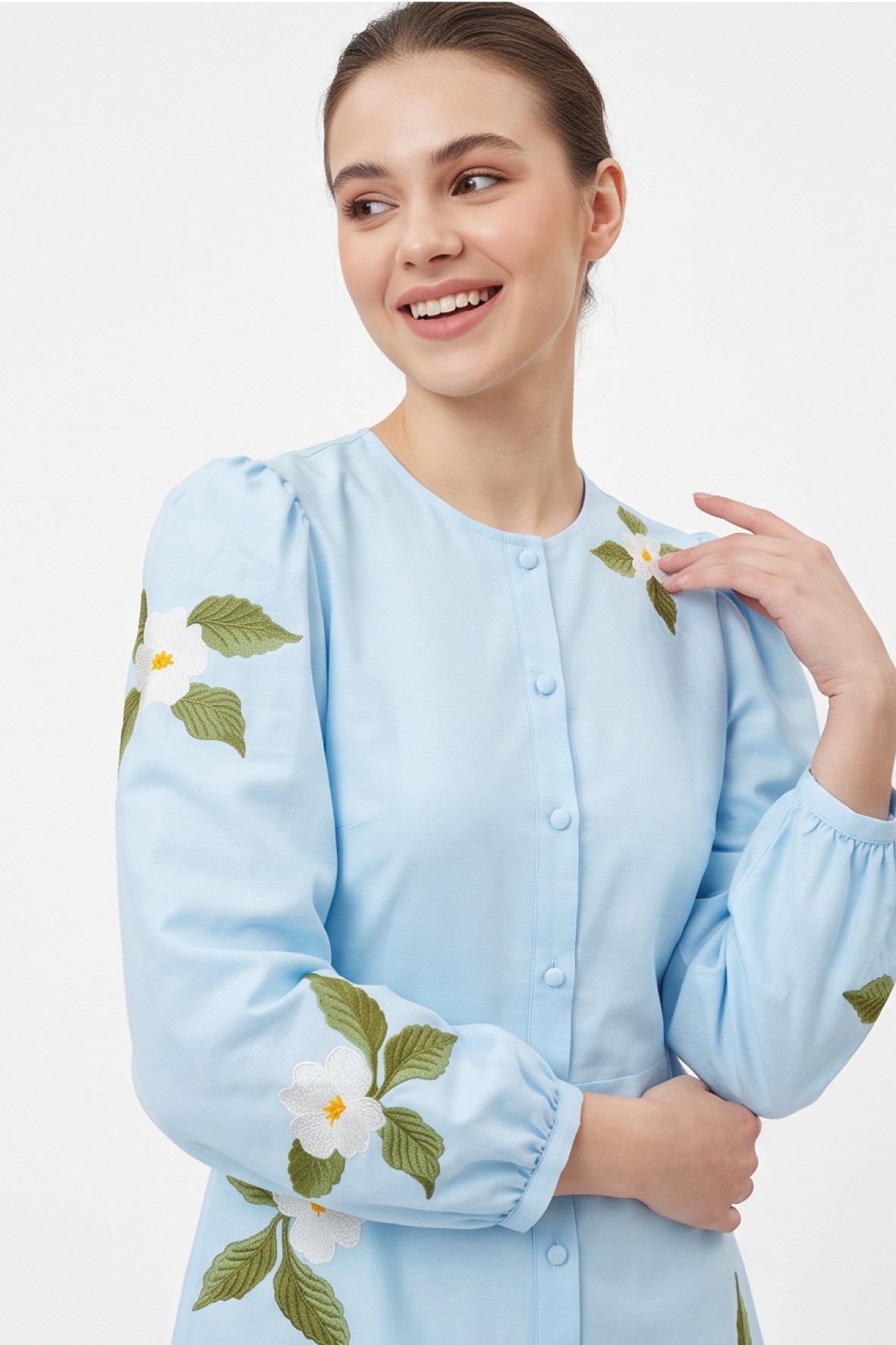 Close-up of Fanm Mon Paysan Dress in light blue showing white floral embroidery, green leaves, fabric-covered buttons, and gathered puff sleeves