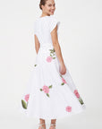 Back view of model wearing Fanm Mon Pervin Dress in white showing the concealed center-back zipper, defined waist, flowing A-line midi skirt, and scattered pink rose embroidery with green foliage.