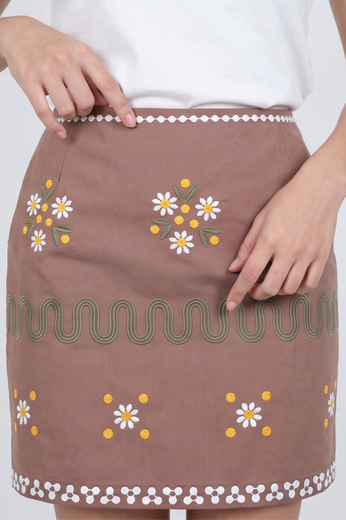 Fanm Mon Roya Skirt detail featuring embroidered daisies, green embroidered wave trim and decorative embroidery at the waist and hem