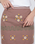 Fanm Mon Roya Skirt detail featuring embroidered daisies, green embroidered wave trim and decorative embroidery at the waist and hem
