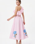 Back view of model wearing the Fanm Mon Tamira Set in light pink showing the cascading ruffles on the one-shoulder crop top and floral embroidery along the flowing midi skirt