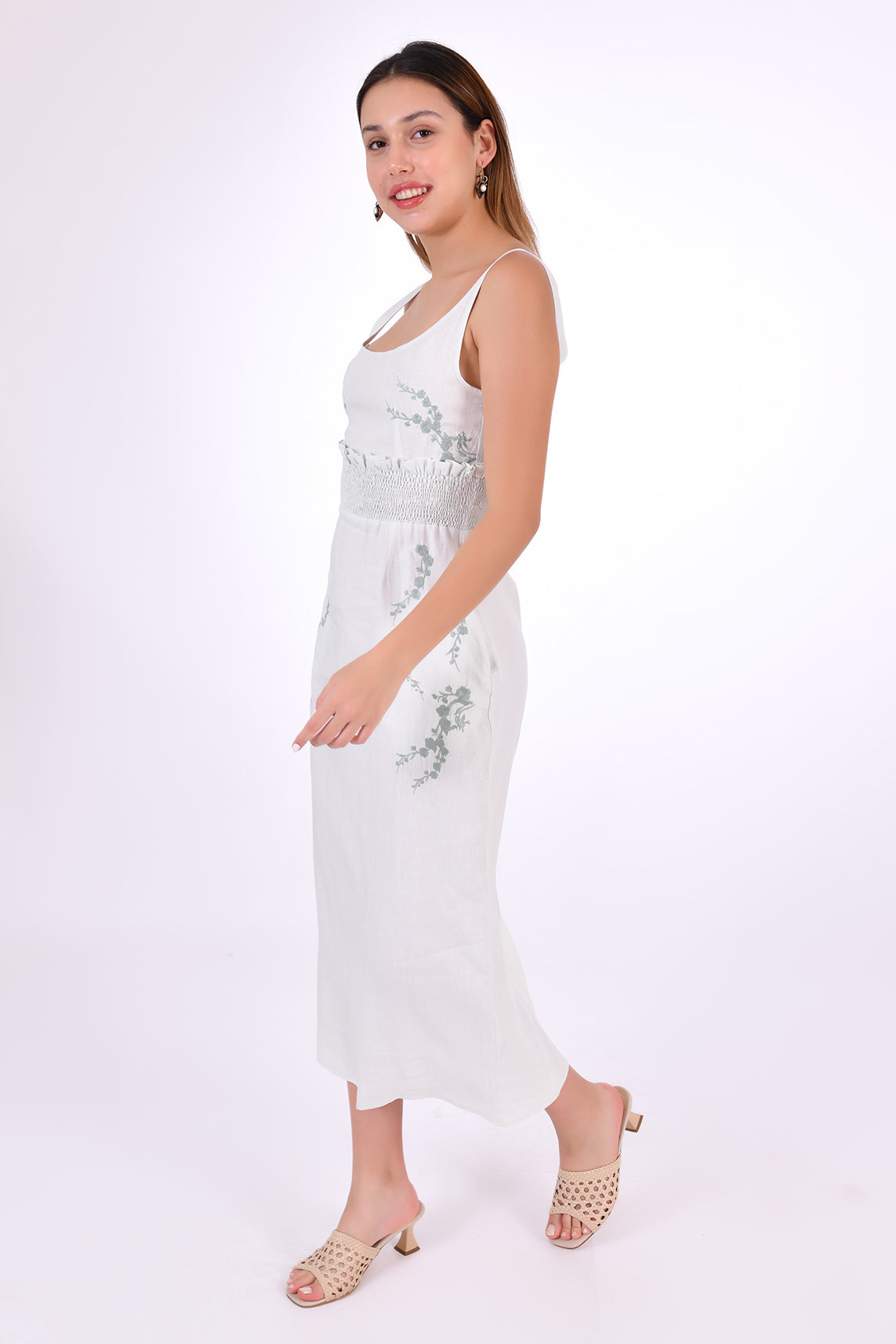 Fanm Mon BAHAR Midi Dress Side View. Sleeveless Midi Linen Sheath Dress. Featuring a smocked waistband with ruffle trim and hand-embroidered floral pattern.