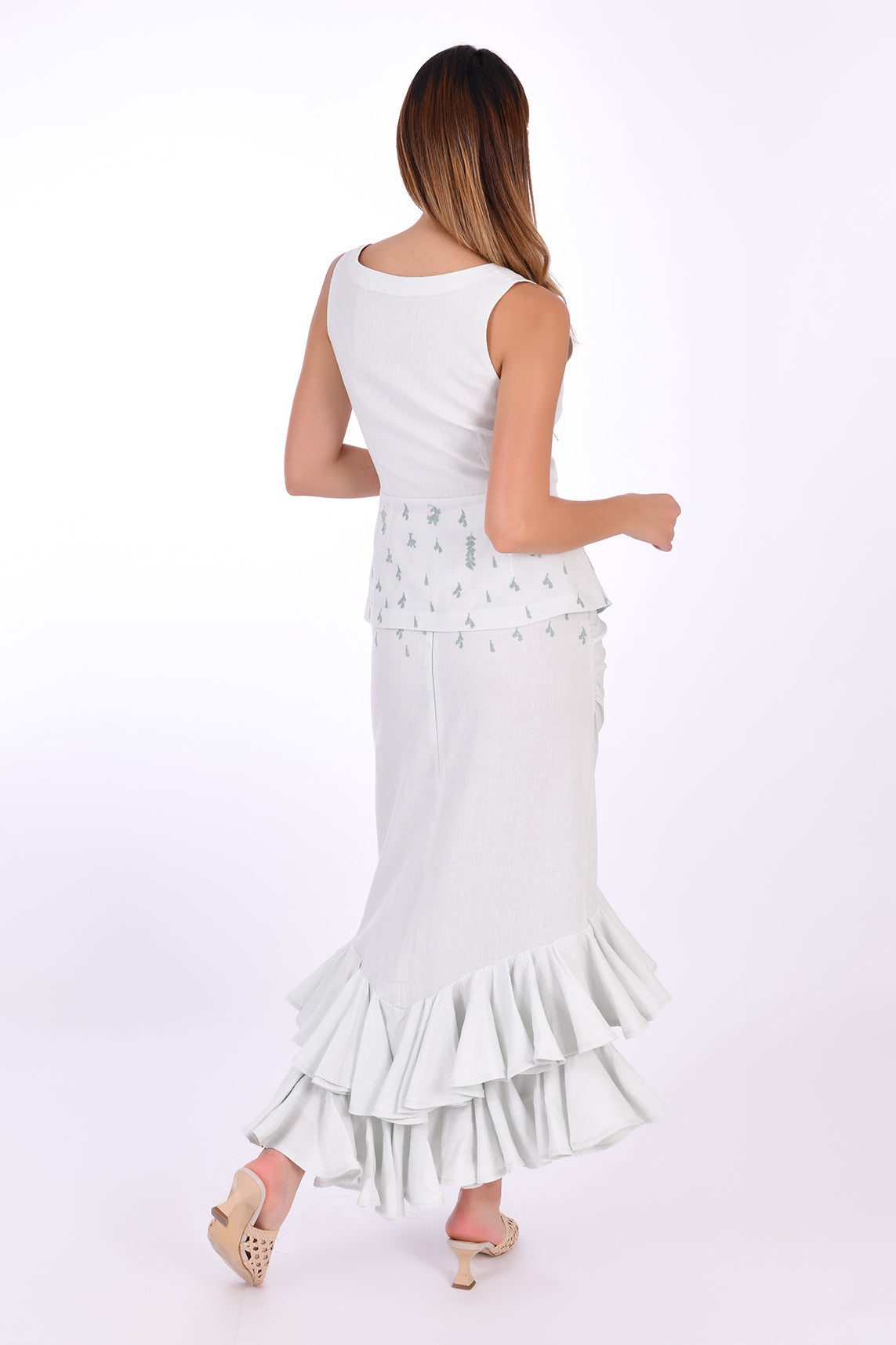 Fanm Mon Flamen Skirt Set, Back View. 2 Piece Linen Top and Skirt Set includes a sleeveless top with a v-neck, a tie-up front, and a peplum flare bottom with delicate embroidery. The midi-length linen skirt is complemented by a gathered front detail and coordinating embroidery.